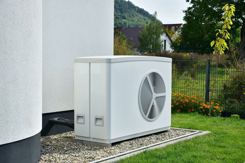 Wärmepumpe im Garten vor einer Hauswand