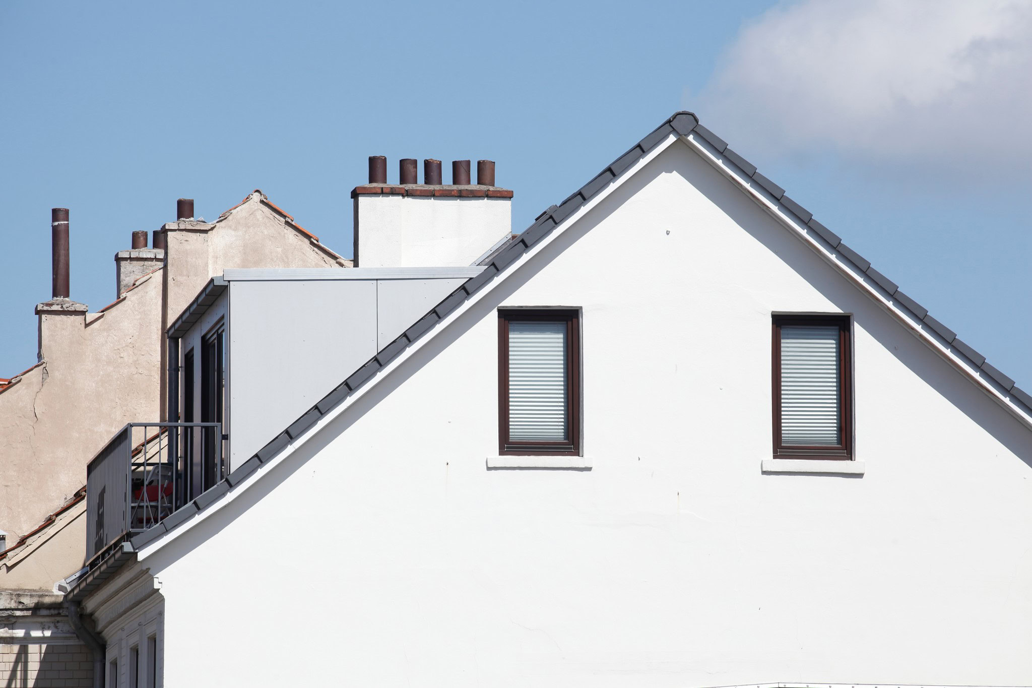 Mehrfamilienhaus mit sanierungsbedürftiger Fassade und moderner Dachaufstockung – typische Ausgangslage für eine Energieberatung.
